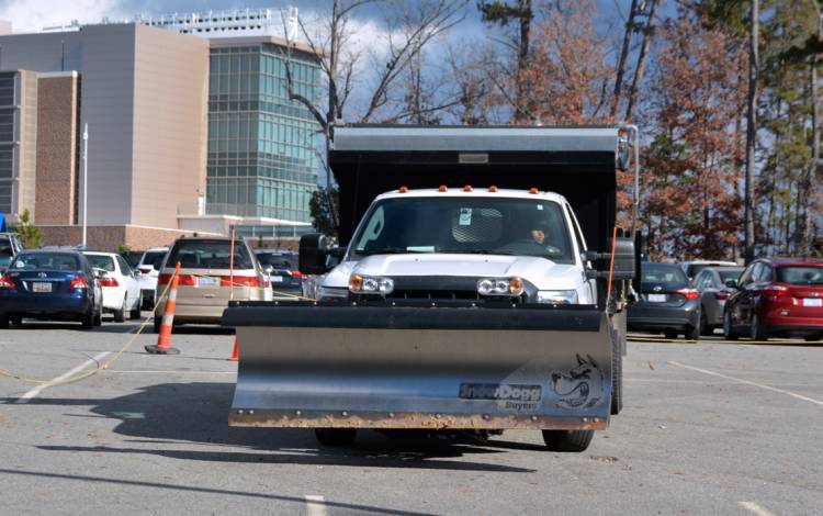 Candi Walker, grounds equipment operator for Duke Facilities, drives a snow plow around an obstacle coursed during the snow rodeo.