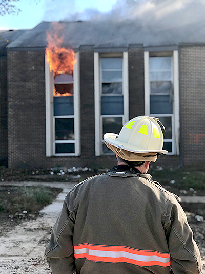 Flames fly out of a window during the fire training exercise. Photo by Hector Hernandez