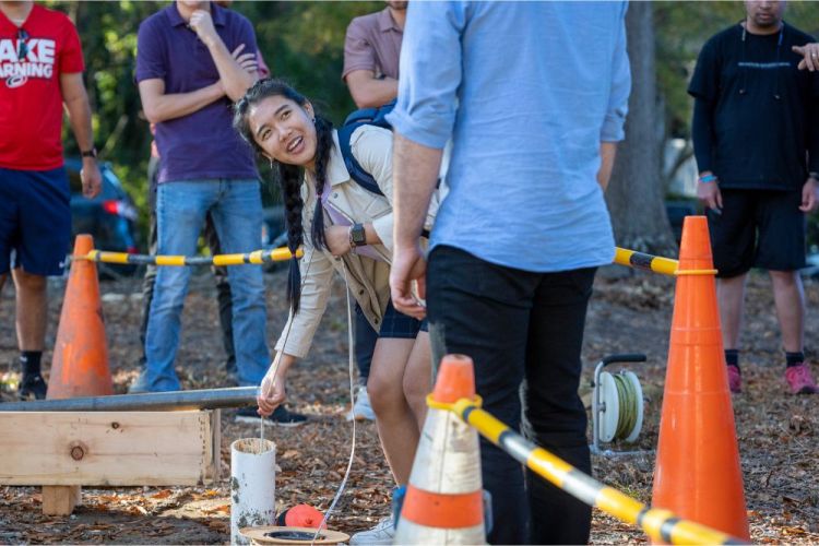 Students watch another student measure hole depth