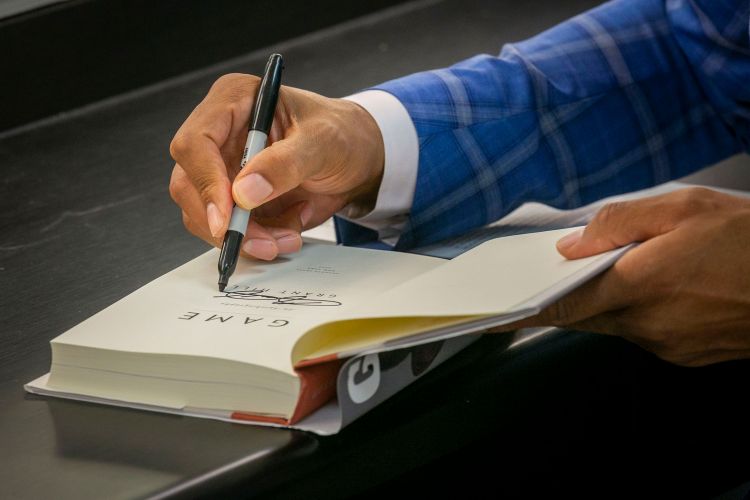 Following the discussion, Hill signs a copy of his autobiography for a reader.