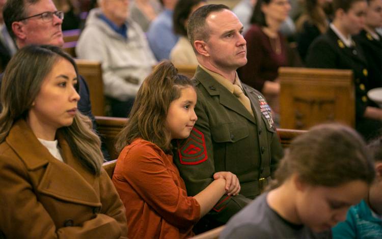 Flanked by his wife Sindy, left, and his daughter Isabella, center, Gunnery Sgt. Robert Weinhardt watches Monday's ceremony. Photo by Jared Lazarus.