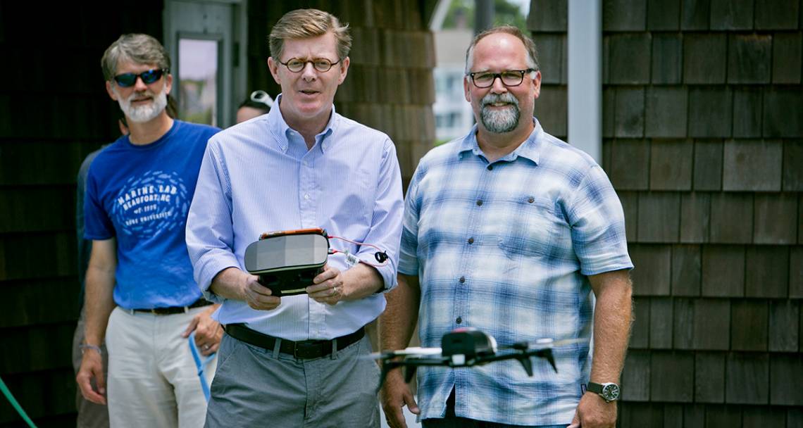 President Vincent Price directs a drone during a visit to the Marine Lab. Professor David Johnston, right, who uses drones to study marine mammals, watches. Photo Jared Lazarus