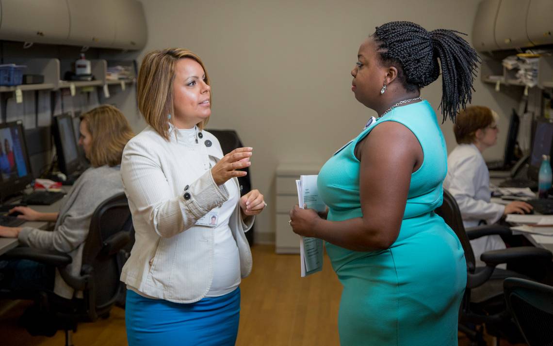 Cinnamon Ruth Leggett, left, talks with a colleague in Duke's 1E Hematology Clinic.