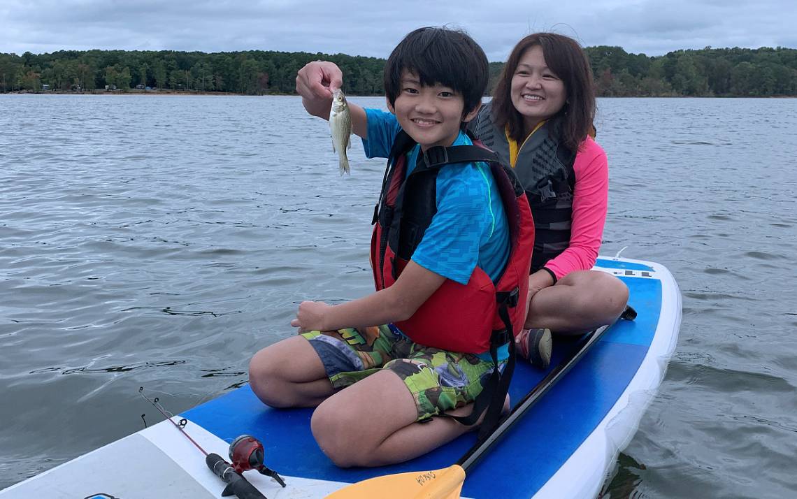 Linda Chang and her son, Jesse, fish on a stand-up paddleboard on Jordan Lake. Photo courtesy of Linda Chang.