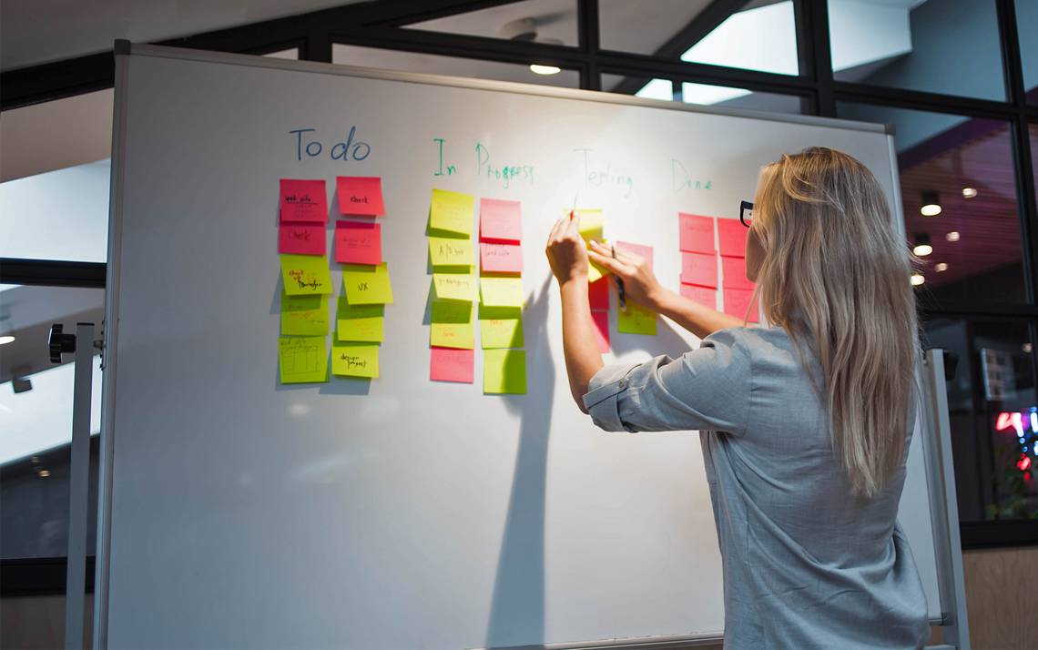 A woman writes notes on a board.