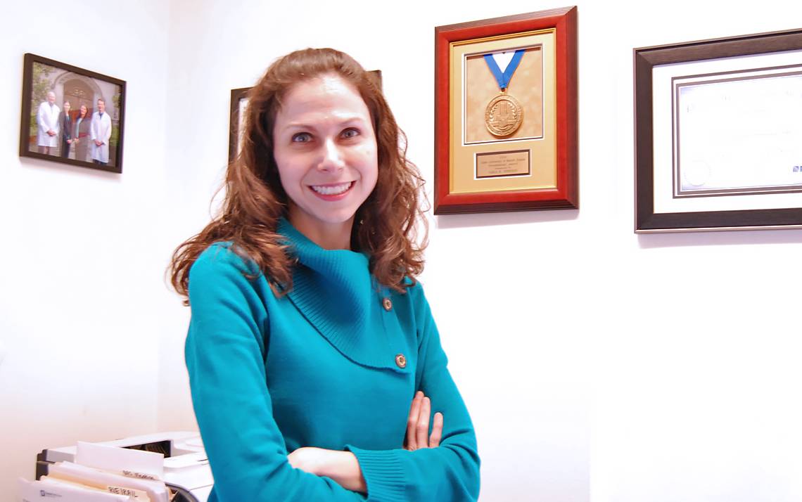 Duke Gastroenterology's Sara Johnson stands in front of the Duke Presidential Award she earned thanks to her innovative solutions to vexing problems.