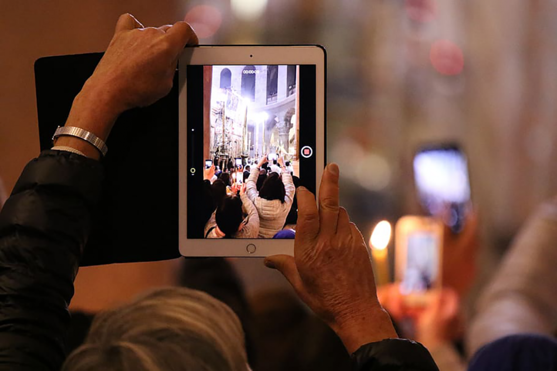 image of a person using a pad computer to record worship service in church