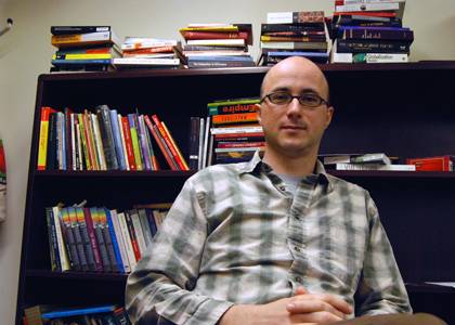 Gustavo Furtado poses by some of the many books decorating his office. Photo by Bryan Roth.