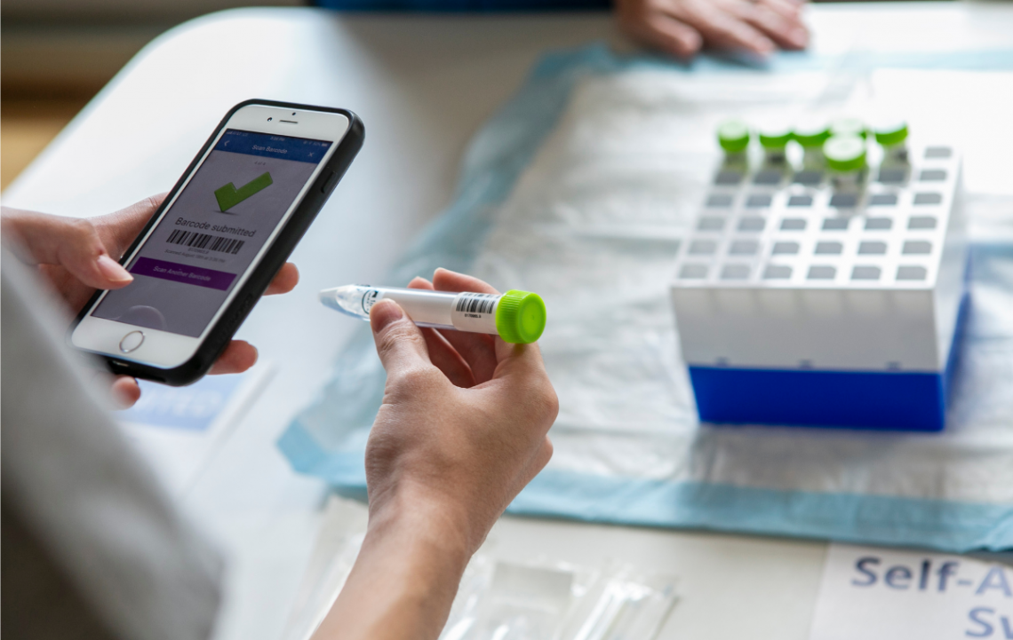 A Duke student is using a cellphone app to scan a vial of saline solution provided in the COVID self-testing kit.