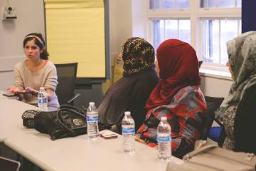 Medical student Rayan Kaakati, a member of a Bass Connections team, talks with refugees living in Durham.