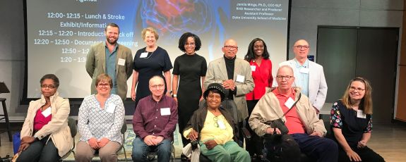A group of 12 people, one row seated, another standing behind, pose for a photo.