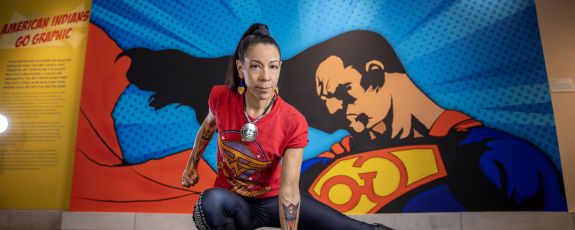 Person kneeling in front of American Indian Go Graphic