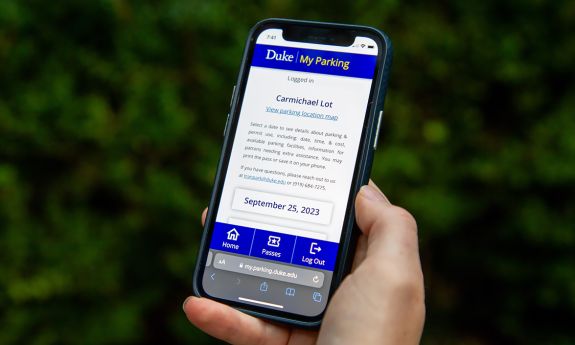 A person holds an iPhone with MyParking on the screen.