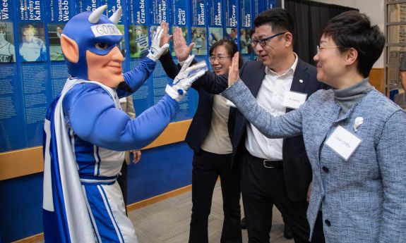 Duke's Blue Devil mascot high-fives representatives from Duke Kunshan University in China