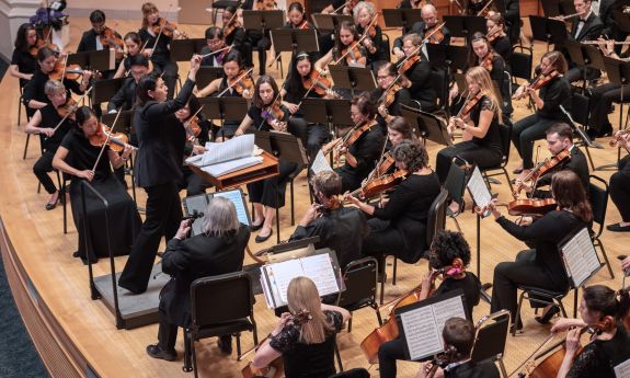 A portion of an orchestra is shown performing on a stage