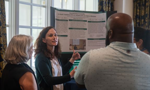 Person standing in front of a presentation board talking to others. 