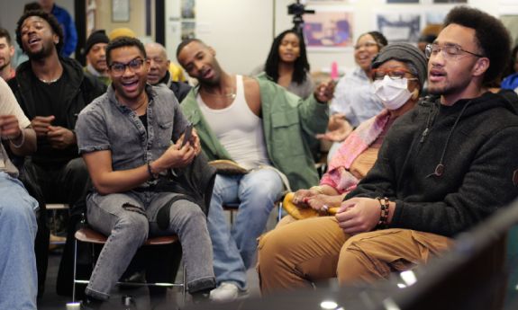 A group of people singing, sitting in chairs