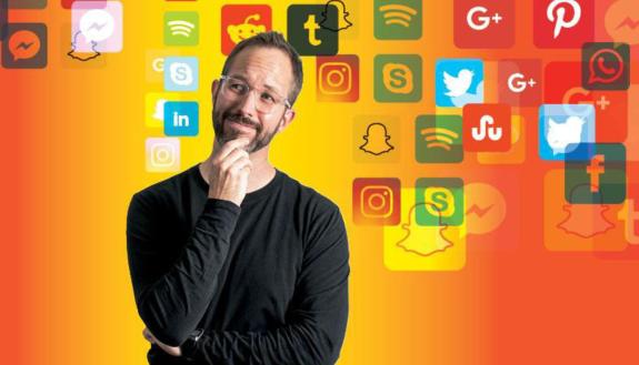 Christopher Bail standing in front of a backdrop of social media logos