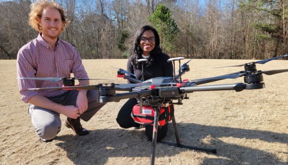 Cardiologist Dr. Monique Starks and drone pilot Evan Arnold, research associate at the Institute for Transportation Research and Education at NC State, take a drone out for a test flight. The AED is attached in the red box underneath the drone. Credit: Elizabeth Switzer, Duke Department of Medicine. 