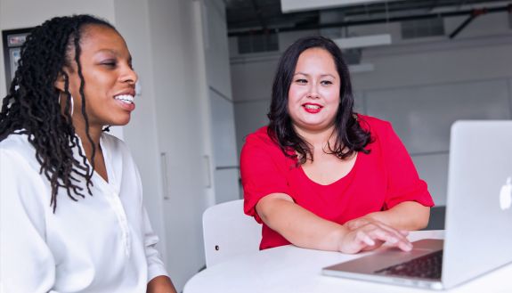 Two professionals look over a laptop together. Photo courtesy of Pexels.