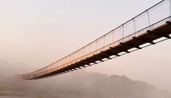 bridge built by Duke students working with community members crossing ravine in 