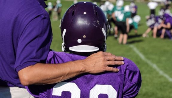 Coach with arm around young football player