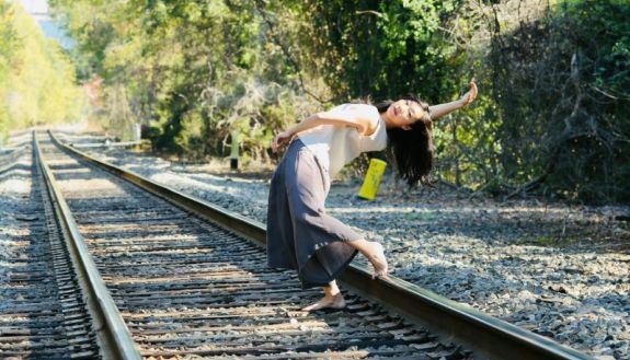 Jingqui Guan dancing on railroad tracks