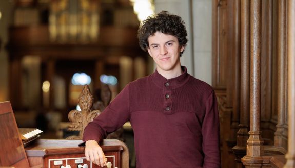 Joey Scarpa stands with his arm resting on the organ