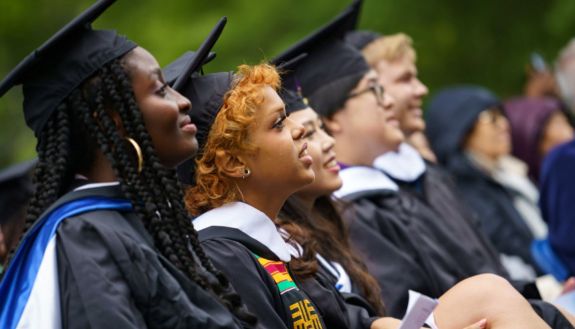 students in caps and gowns looking at a speaker