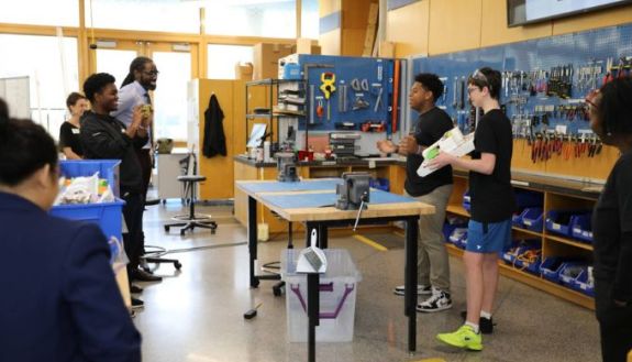 students in a shop type class in middle school, with lots of tools behind them