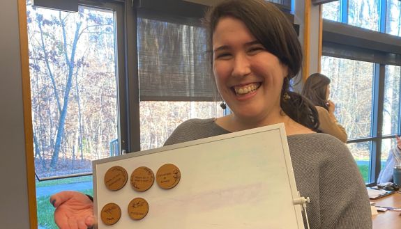 Sarah Barton holds up a board with magnets on it. 
