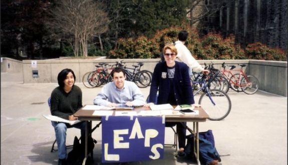 Photo from the 90s showing people sitting at a table with a LEAPS sign
