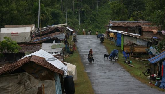Makeshift huts made in Indonesia, with children playing in the road.
