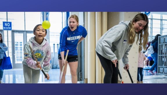 Field hockey players help young girls raise their skills.