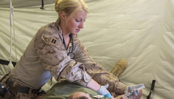 Erika Grattidge in military gear with a patient