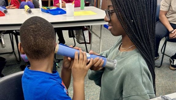 Durham youth listens to a heart beat of a duke student teaching about health and science