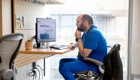 Person in medical garb looking at a computer