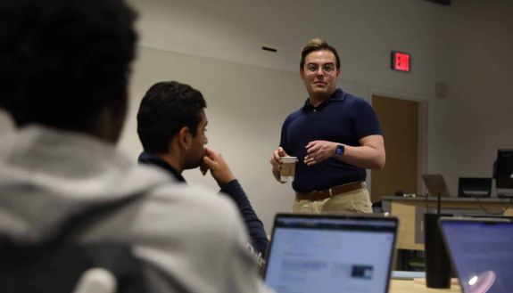 Person standing in front of students with their computer open