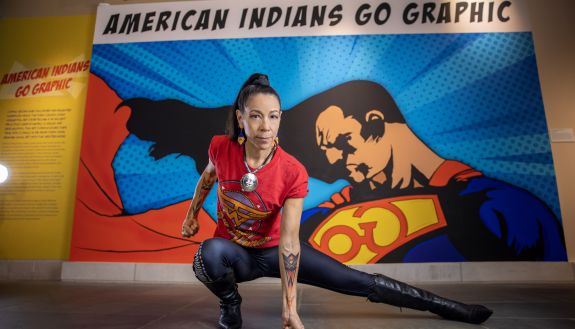 Person kneeling in front of American Indian Go Graphic