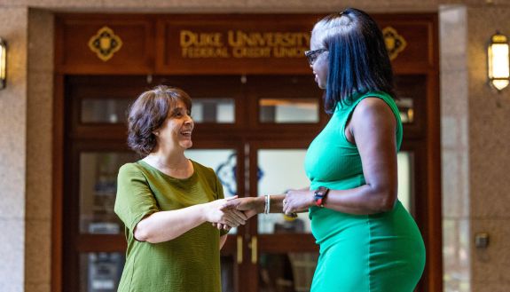 Two women shake hands outside the Duke Credit Union