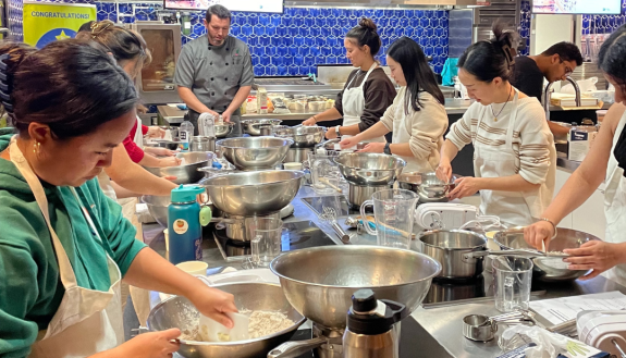 A group of people cooking in a kitchen.