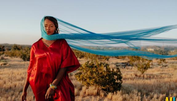 Photo of Muslim woman in red dress and head scarf against windy background