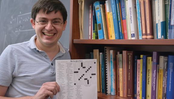 Adam Levine, associate professor in the Duke University Department of Mathematics, holds the crossword puzzle he created for The New York Times. Photos by Stephen Schramm.