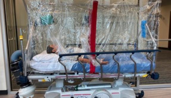 Photo of mannikin in COVIAGE tent, a portable isolation chamber