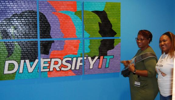 Attendees Trina Rodriguez, left, and La’Shawnda Kendall pose in front of the DiversifyIT art piece called A Work In Progress on Aug. 29. Photo by Jack Frederick