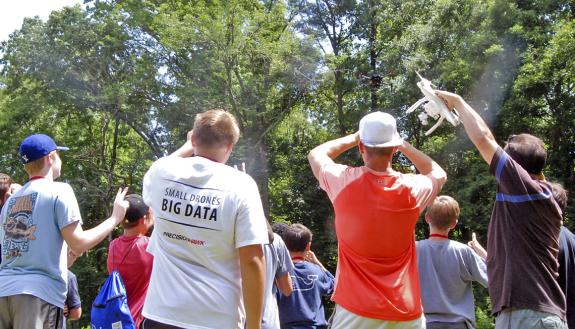 Kids watch a drone fly in Duke Forest.