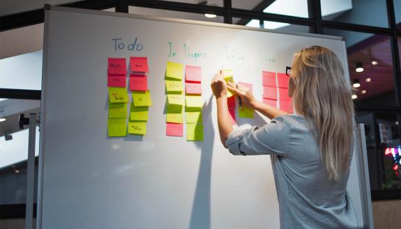 A woman writes notes on a board.