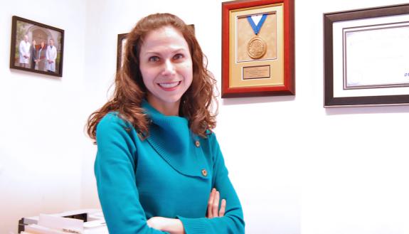 Duke Gastroenterology's Sara Johnson stands in front of the Duke Presidential Award she earned thanks to her innovative solutions to vexing problems.