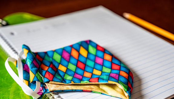 graphic image of covid mask on top of school notebook