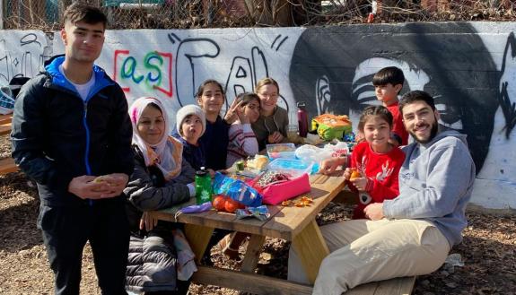 Political Science Ph.D. candidates Patrick Ramjug (right) and Emily Myers (sixth from left) hang out with members of the Afghan family they are supporting. (Photo courtesy of Patrick Ramjug)